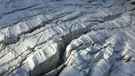 Rotating-cinematic-aerial-drone-shot-of-many-crevasses-through-the-Ak-Sai-glacier
