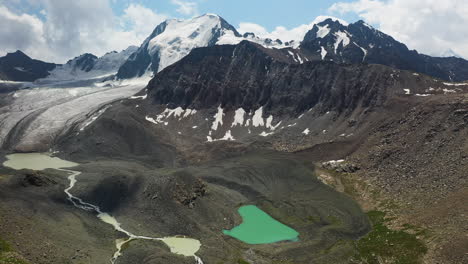 Wide-aerial-drone-shot-of-the-surrounding-land-around-the-Ala-Kol-lake-and-glacier-in-Kyrgyzstan