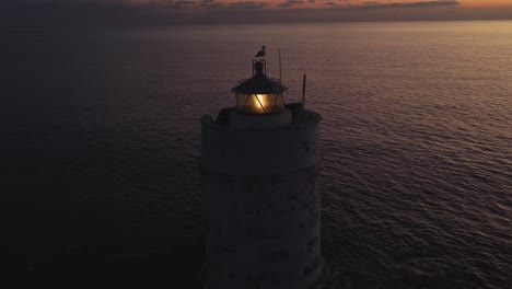 Wonderful-aerial-drone-shot-of-solitary-Lighthouse-with-seagull-on-top,-dusk