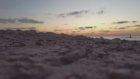 Niedrige-Statische-Aufnahme-Des-Geländes-Mit-Offshore-Leuchtturm-Im-Hintergrund,-Sonnenuntergang