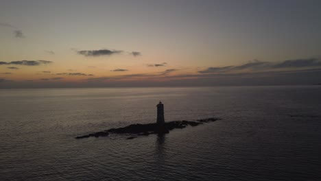 Cinematic-establisher-aerial-shot-of-solitary-Lighthouse-in-middle-of-sea,-dusk