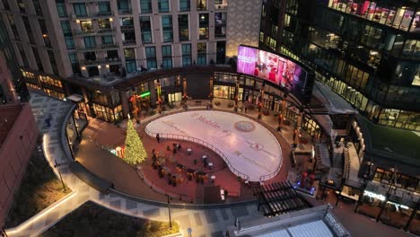 Evening-aerial-view-of-McGregor-Square-in-Denver,-Colorado-with-an-outdoor-ice-rink-and-lit-up-Christmas-tree