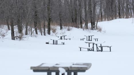 Wide-shot-of-picnic-tables-on-the-beach-covered-in-snow