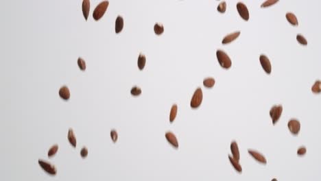 Whole,-raw-almond-nuts-raining-down-on-white-backdrop-in-slow-motion