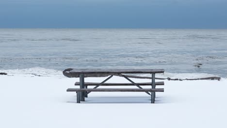 Wide-shot-of-a-picnic-table-on-a-snowy-beach