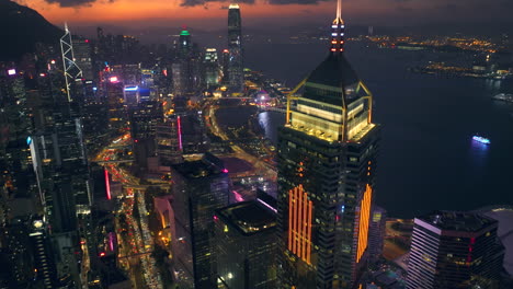 Aerial-tilt-down-of-Hong-Kong-skyline-and-Victoria-Harbour-after-sunset---prominent-skyscraper-Central-Plaza-in-foreground,-Central-financial-district-in-background