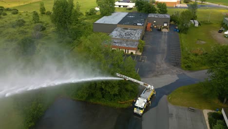 Drohnenaufnahme-Eines-Feuerwehrautos-Mit-Voll-Ausgefahrener-Leiter,-Die-Im-Rahmen-Einer-Trainingsübung-Wasser-Sprüht