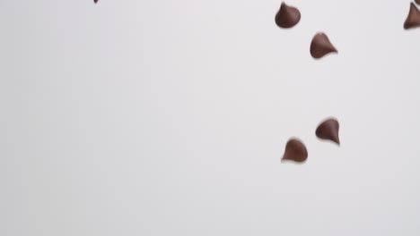 Unwrapped-milk-chocolate-Hershey-kiss-candies-raining-down-on-white-backdrop-in-slow-motion