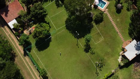 Top-View-Of-Beautiful-Rest-Cottage-House-With-Blue-Pool-Near-Green-Sports-Courts
