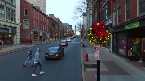 Aerial-reveal-of-city-street-from-Christmas-wreath-on-lamp-post-on-cold-winter-december-day-in-America