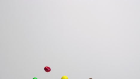 Bright-colored-chocolate-covered-peanut-m-and-m-candies-raining-down-in-slow-motion-on-white-backdrop