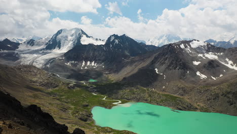 Revealing-drone-shot-of-3-men-standing-on-a-mountain-top-overtop-the-Ala-Kol-lake-in-Kyrgyzstan