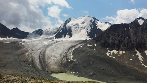 Toma-Aérea-De-Un-Dron-De-Una-Montaña-Cubierta-De-Nieve-Y-Un-Glaciar-A-Lo-Largo-Del-Lago-Ala-kol-En-Kirguistán