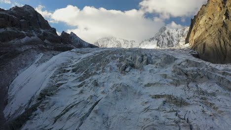 Aufschlussreiche-Filmische-Drohnenaufnahme-Eines-Abwärts-Führenden-Hügels-In-Eine-Öffnung-Durch-Den-Ak-Sai-Gletscher-In-Kirgisistan