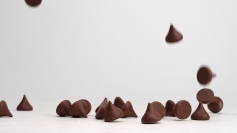 Unwrapped-Hershey-chocolate-kisses-falling-and-bouncing-around-on-white-table-top-in-slow-motion