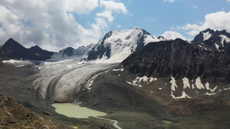 Luftschwenkdrohnenaufnahme-Eines-Schneebedeckten-Berges-Und-Gletschers-Entlang-Des-Ala-Kol-Sees-In-Kirgisistan