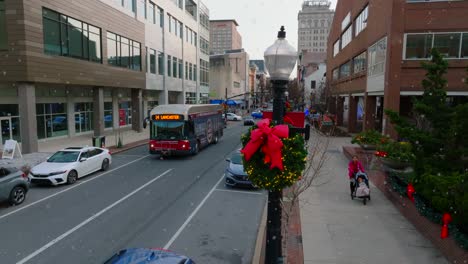 Aerial-orbit-reveal-of-city-bus-driving-through-downtown-street-in-Lancaster-Pennsylvania