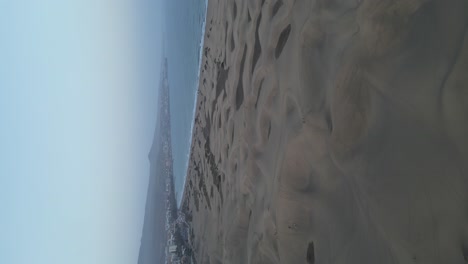 Vertical-video-of-sandy-Dunes-from-Maspalomas-dunes-at-Gran-Canaria-Coastline-at-Sunrise,-Orbiting