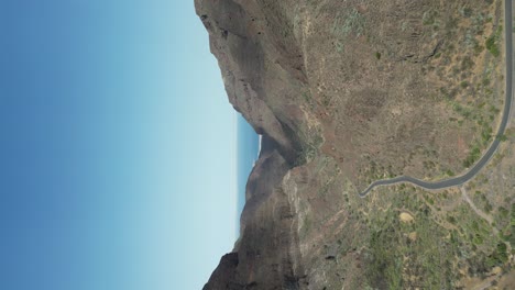 Vertical-video-of-Mountain-road-in-Rocky-valley-towards-Atlantic-Ocean,-Canary-island