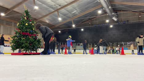 Static-low-angle-view-of-many-kids-ice-skating-in-an-indoor-rink-at-Christmas-in-Majadahonda,-Madrid