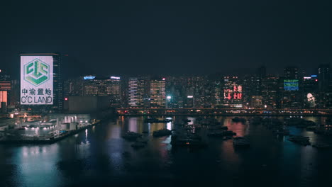 Sideways-shot-of-Kwun-Tong-district-with-moored-boats-in-foreground-and-illuminated-buildings-in-background-during-a-suspenseful-and-dark-evening