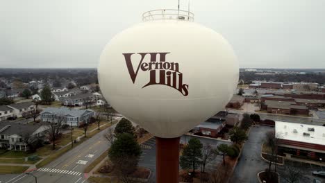 aerial-close-up-of-vernon-hills,-illinois-logo-on-a-water-tower,-flying-and-revealing-the-city