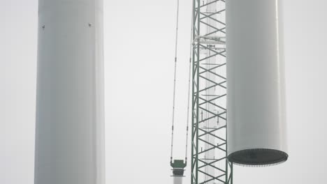Construction-process-of-a-wind-turbine,-hoisting-of-an-electric-energy-generating-blade-with-a-crane,-still-shot