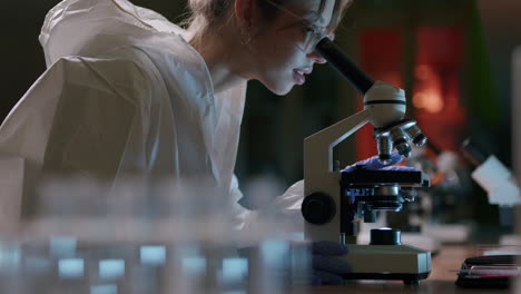 Female-scientist-with-protective-gear-use-microscope-in-laboratory