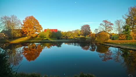 Timelapse-shot-of-houses-beside-a-lake-in-front-from-morning-to-evening-time-on-a-autumn-day