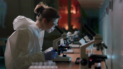 Weibliche-Mikrobiologin,-Die-Probe-Mit-Mikroskop-Im-Labor-Analysiert