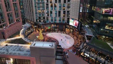 Outdoor-Ice-Skating-Rink-at-McGregor-Square-Denver-Downtown-During-Christmas,-Aerial-Tilt-Down-View,-Urban-Living-and-Entertainment