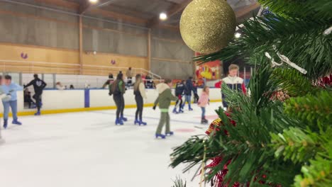 Viele-Junge-Unscharfe-Leute-Eislaufen-Auf-Einer-Eisbahn-Mit-Einem-Weihnachtsbaum-Im-Vordergrund
