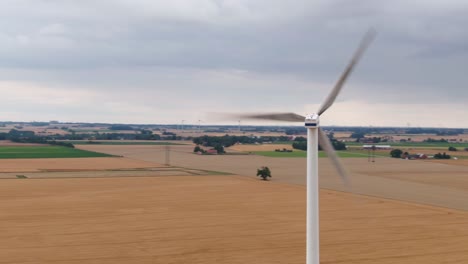 Wide-drone-shot-showing-vast-fields-and-farming-with-wind-turbine-in-foreground