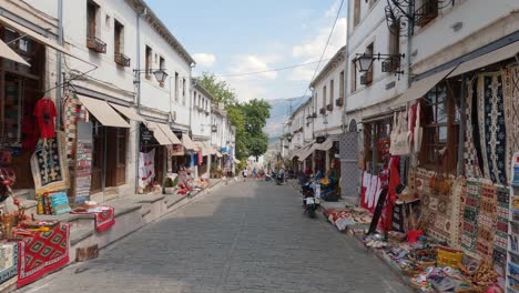 Antiguo-Bazar-Sobre-Caminos-De-Piedra-Y-Ladrillo,-Bordeado-De-Candelabros-Y-Un-Telón-De-Fondo-De-Las-Montañas-Gjere-En-Gjirokaster,-Albania