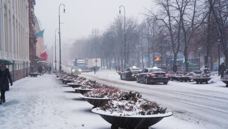 Nieve-Cayendo-Sobre-La-Puerta-De-Karl-Johans-Con-Tráfico-Pasando-Lentamente-En-Oslo
