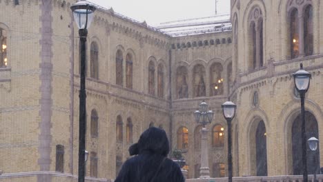 People-Walking-Past-The-Norwegian-Parliament-Building-In-Background-During-Heavy-Snow