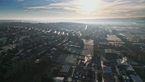Cold-winter-morning-aerial-footage-of-a-town-city-landscape,-with-low-afternoon-lighting-and-freezing-sunlit-houses