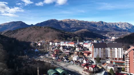 Aerial-view-of-Sinaia-town-with-mountains-and-ski-resorts-in-Prahova-County,-Romania-during-sunny-day,Romania