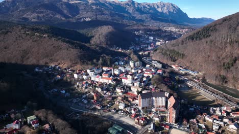 Aerial-birds-eye-shot-of-small-mountain-city-of-Sinaia-during-sunny-day-in-Romania---Tilt-up-shot