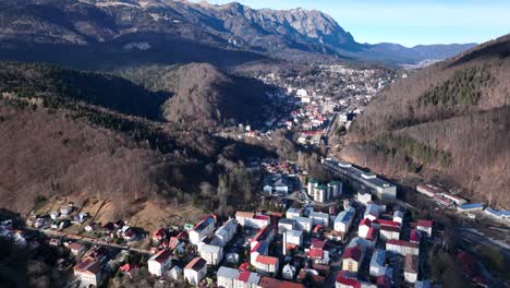 Drone-flight-above-small-Romanian-city-between-mountains-during-sunny-day-in-the-morning---Sinaia,-Romania
