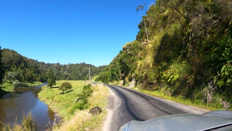 An-Einem-Sonnigen-Tag-Auf-Der-Straße-Mit-Der-Landschaft-Der-Grünen-Felsigen-Berge-In-Taranaki,-Neuseeland-Fahren