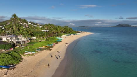 Playa-De-Lanikai-En-Cámara-Lenta-De-60-Fps-Al-Amanecer-Con-Mucha-Gente-En-La-Playa-Y-El-Océano-Azul-Y-Casas-Palmeras-Canoas-Y-Montañas-En-Oahu-Hawaii