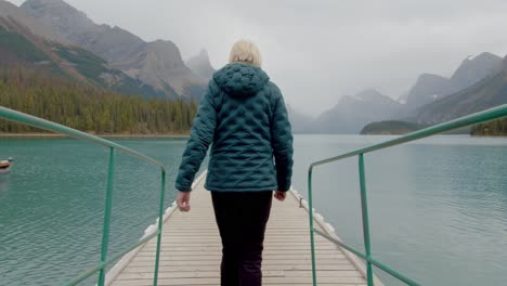 Mujer-Al-Aire-Libre-Caminando-Por-Un-Muelle-En-Un-Impresionante-Lago-En-Las-Montañas-Rocosas-Canadienses