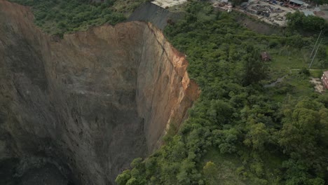 Aerial-tilt-reveals-scaling-of-vertical-rock-cliff-in-open-pit-mine