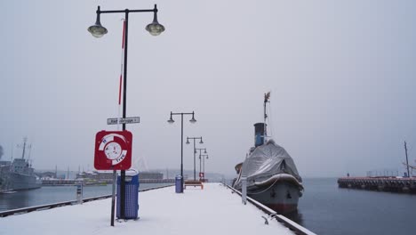 Moored-Boat-With-Covered-Forward-Bow-Tied-To-Snow-Covered-Pier-Dock-At-Aker-Brygge-In-Winter