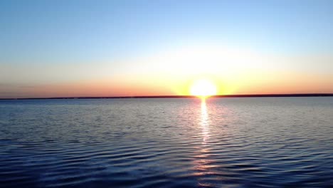 Pulsierendes-Sonnenlicht-Bei-Tagesanbruch-über-Idyllischem-See-Mit-Holzboot-Vor-Der-Küste