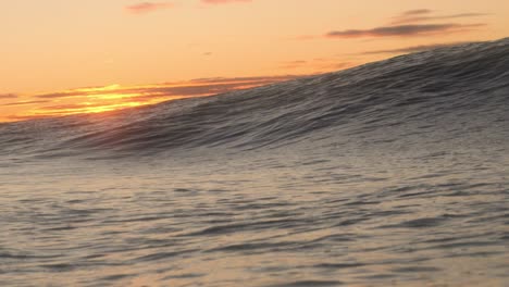 A-short-heavy-wave-crash-over-the-shallow-rock-ledge-as-the-sun-rises-in-the-background