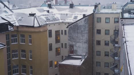 Snow-Being-Blow-Off-Rooftop-Behind-Apartment-Buildings-In-St