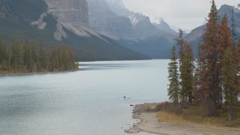 Kayaker-paddling-through-an-island-in-the-middle-of-stunning-lake-surrounded-by-the-Canadian-rocky-mountains