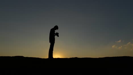Silhouettenfotograf-Sonnenuntergang-Klarer-Himmel,-Fotografiert-Und-Schaut-Dann-In-Die-Kamera